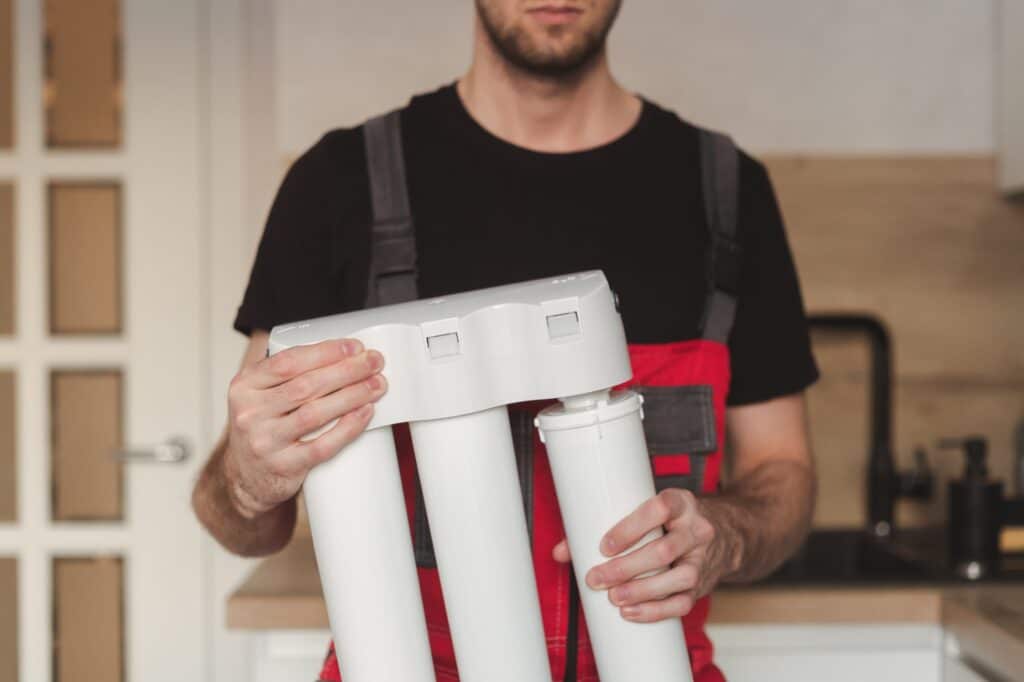 Plumber upgrading a water filtration system, highlighting the role of proper water softener grain capacity in optimizing home water quality.